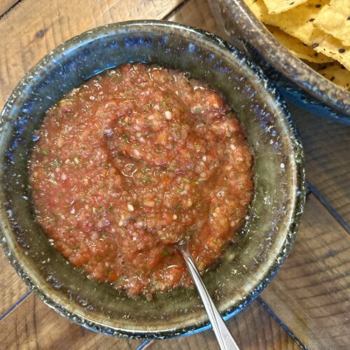 Fresh salsa in a bowl next to a bowl of chips.