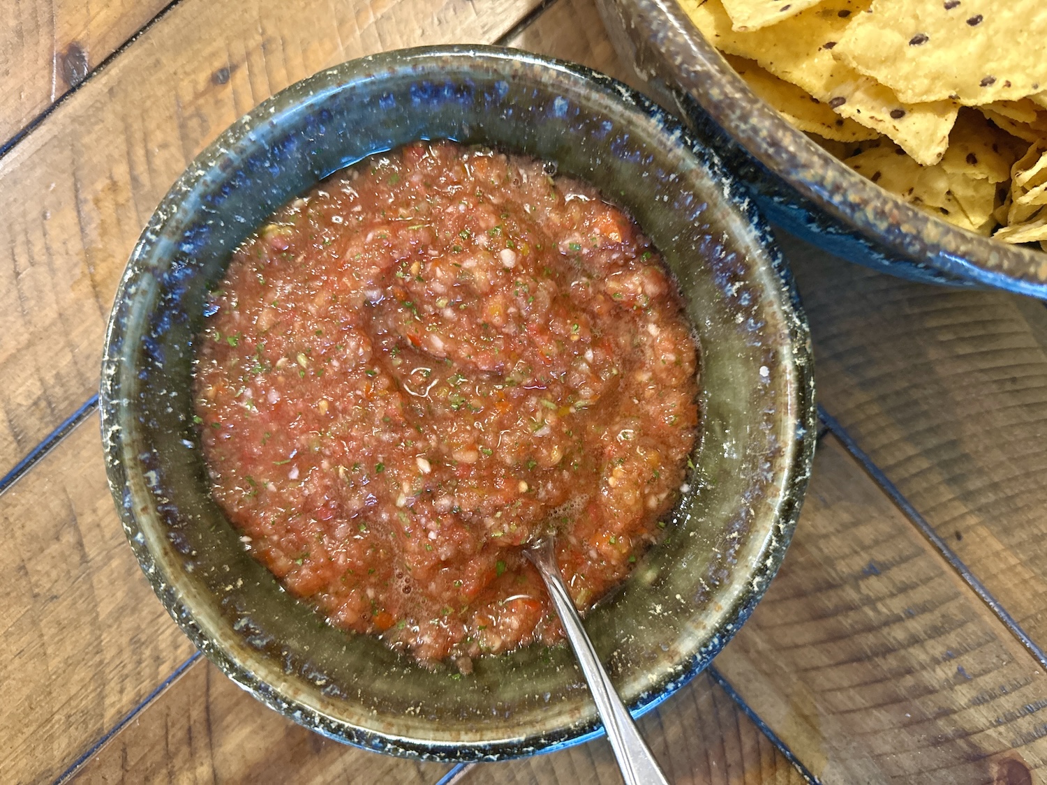 Fresh salsa in a bowl next to a bowl of chips.