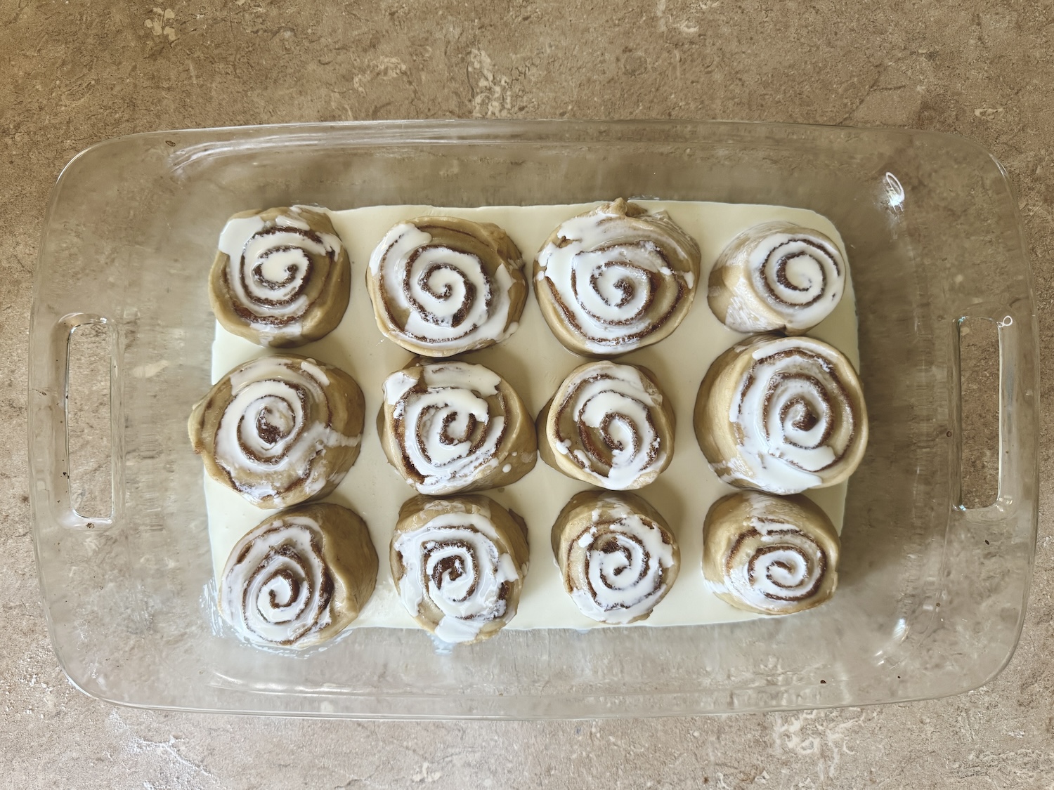 cinnamon rolls in baking dish with heavy cream