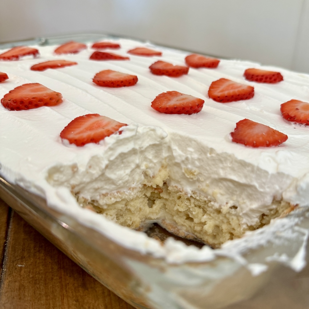 Freshly made tres leches cake with strawberries on top.