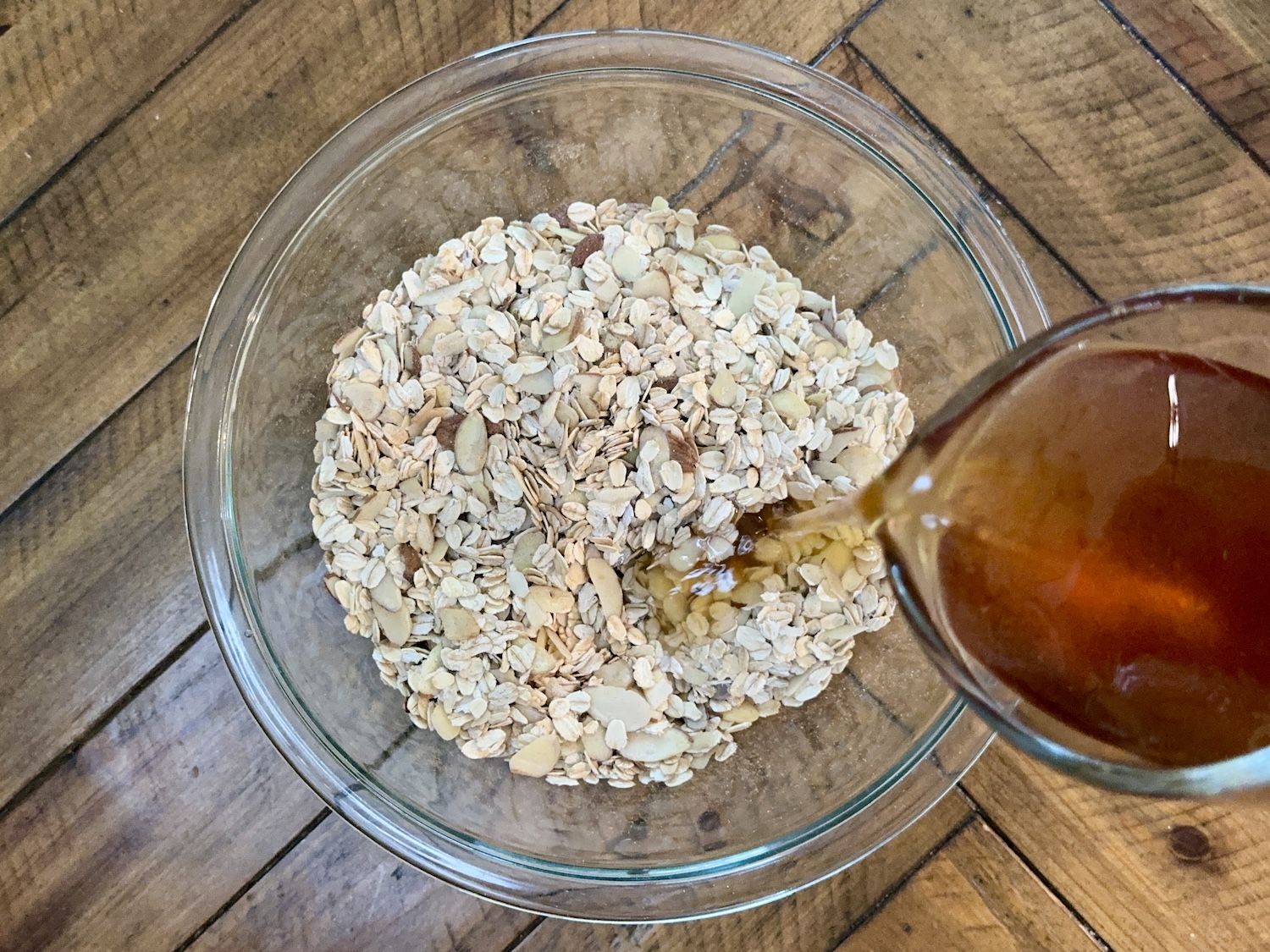 pouring in syrup to dry granola ingredients